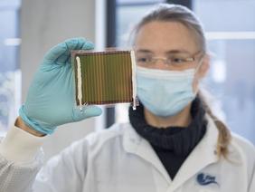 Eine Wissenschaftlerin hält ein semitransparentes Perowskit-Solarmodul in die Kamera. Foto: ZSW